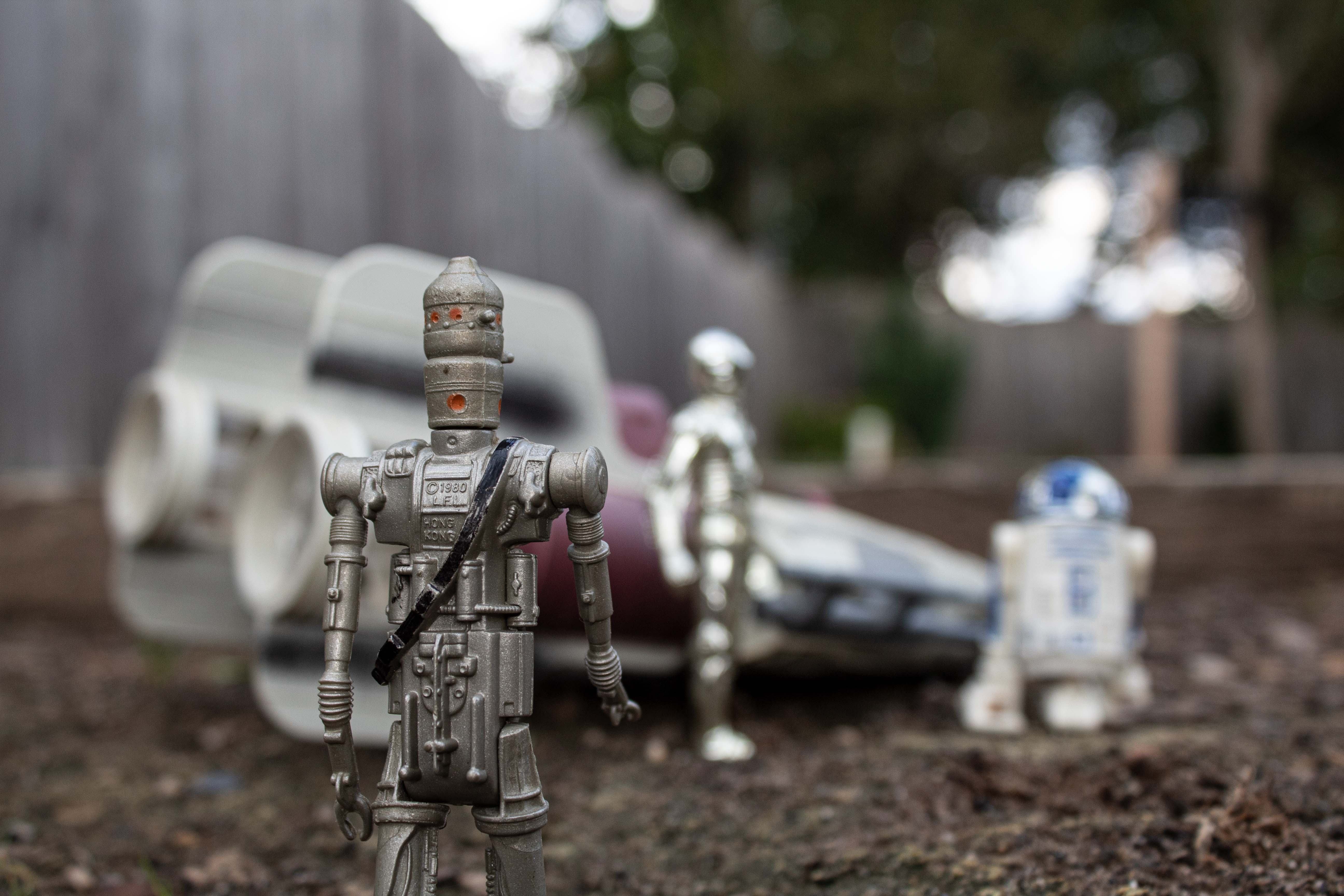 action figures shot at a low angle to make them look life like. 3-CPO is standing right infront of the camera lens with a blurred background of a ship and two other figures.